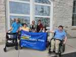 Brad, Maddy, Kayla, Meg, Kelsey and Justin gather together to hold the National AccessAbility Week flag.